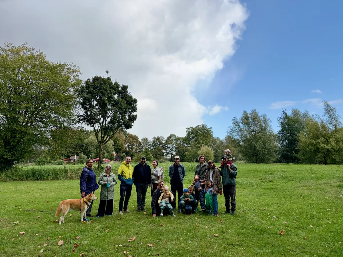 Menschen aus der Mahala-Gemeinschaft mit Kindern und Hund auf einer grünen Wiese